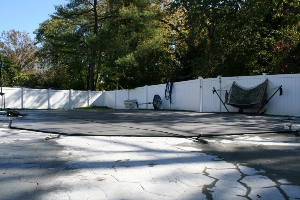 A covered pool surrounded by a white fence.