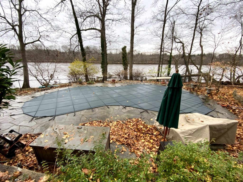 A pool covered for the fall and winter seasons located near a body of water.